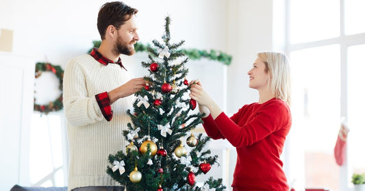 young couple decorating a small christmas tree in a small space
