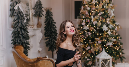 classy woman holding a champagne glass while surrounded by Christmas trees