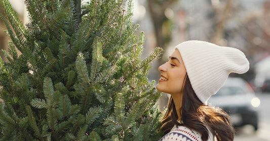 woman at a christmas tree farm picking a tree and smelling one
