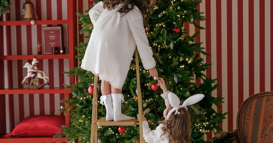 little sisters decorating a tall christmas tree