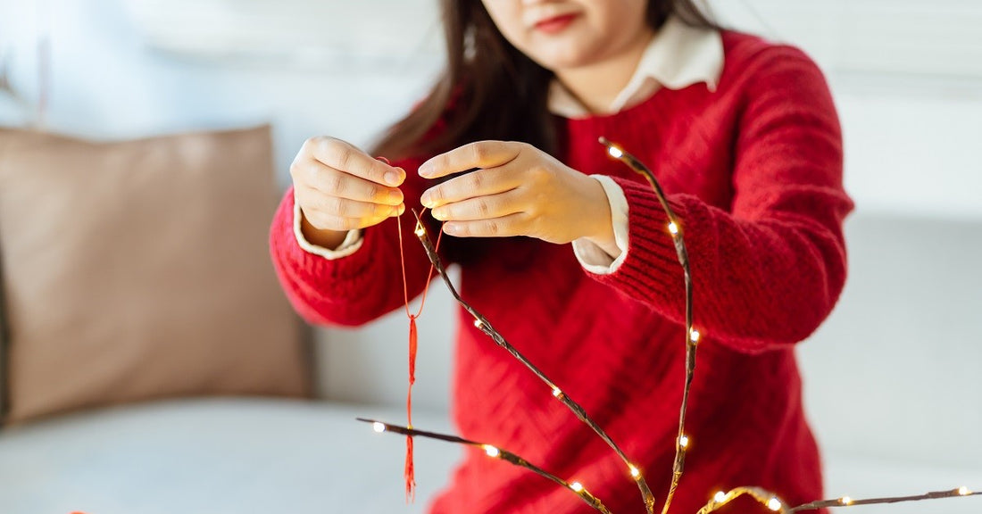 smiling woman stringing christmas lights on a tree