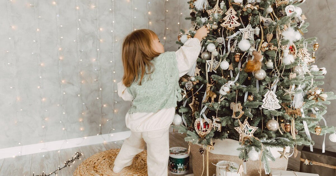 little girl reaching up to decorate the christmas tree